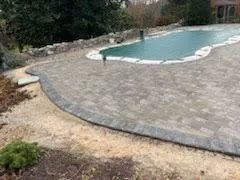 Stone patio surrounding a pool covered by a tarp.