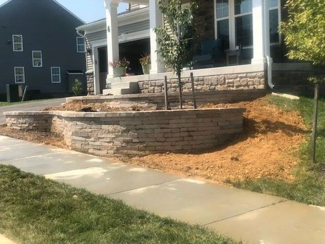 Stone retaining walls and steps leading up to a house with a porch.