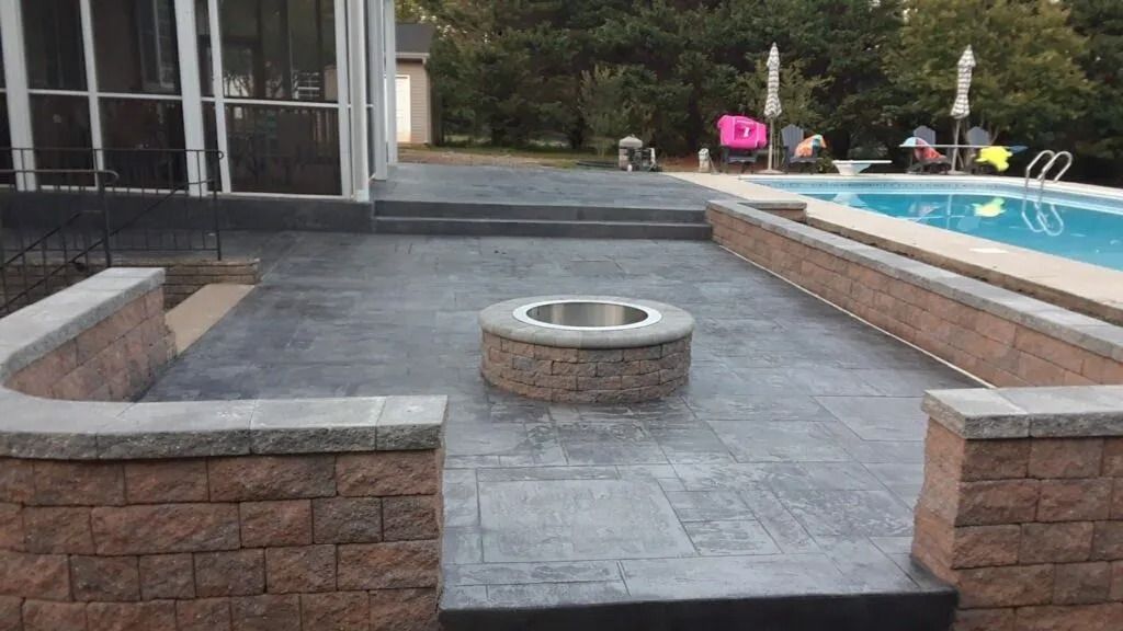 Patio with fire pit, brick walls, steps, and pool in a backyard setting.