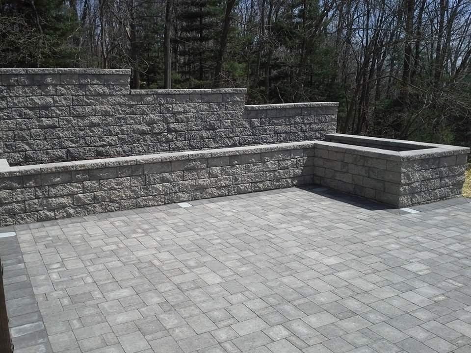 Stone patio with tiered retaining walls and a built-in planter. Gray paving stones.