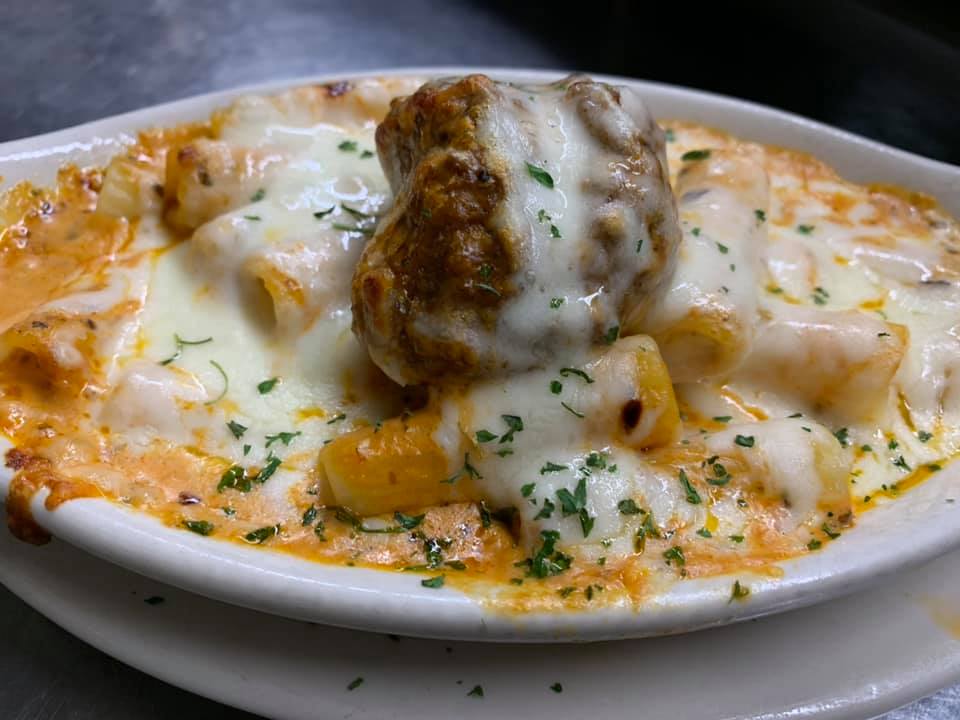 A close up of a plate of food with meatballs and cheese on a table.