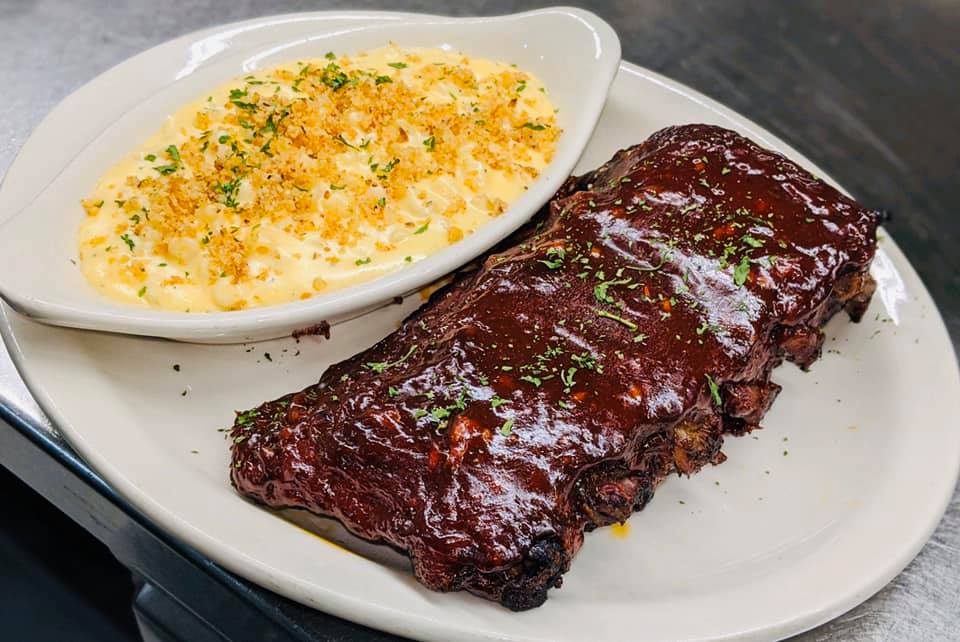 A plate of ribs and macaroni and cheese on a table.