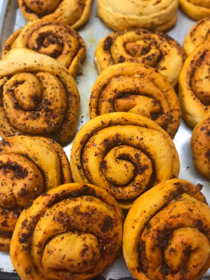 A bunch of cinnamon rolls are sitting on a tray on a table.