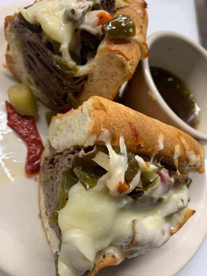 A close up of a sandwich on a plate with a cup of dipping sauce.