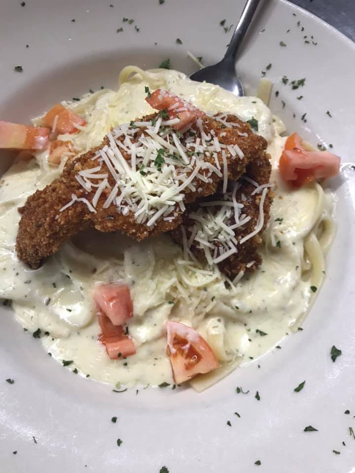 A close up of a plate of pasta with chicken and tomatoes
