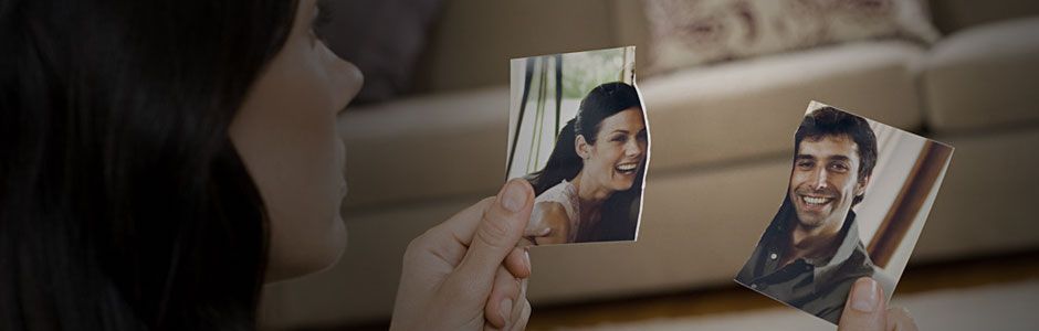Woman holding a torn picture of herself and her ex