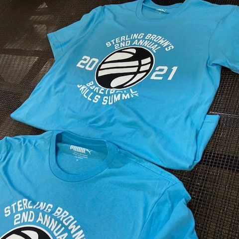 Two blue t-shirts are sitting next to each other on a table.