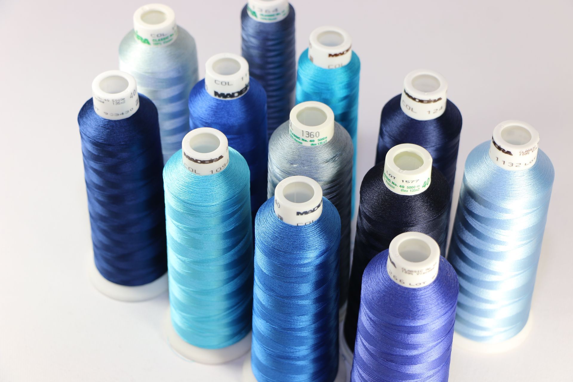 Several bottles of blue thread are lined up on a table
