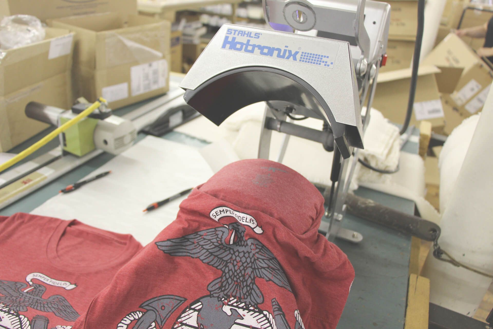 A red shirt with an eagle on it is being printed on a machine.
