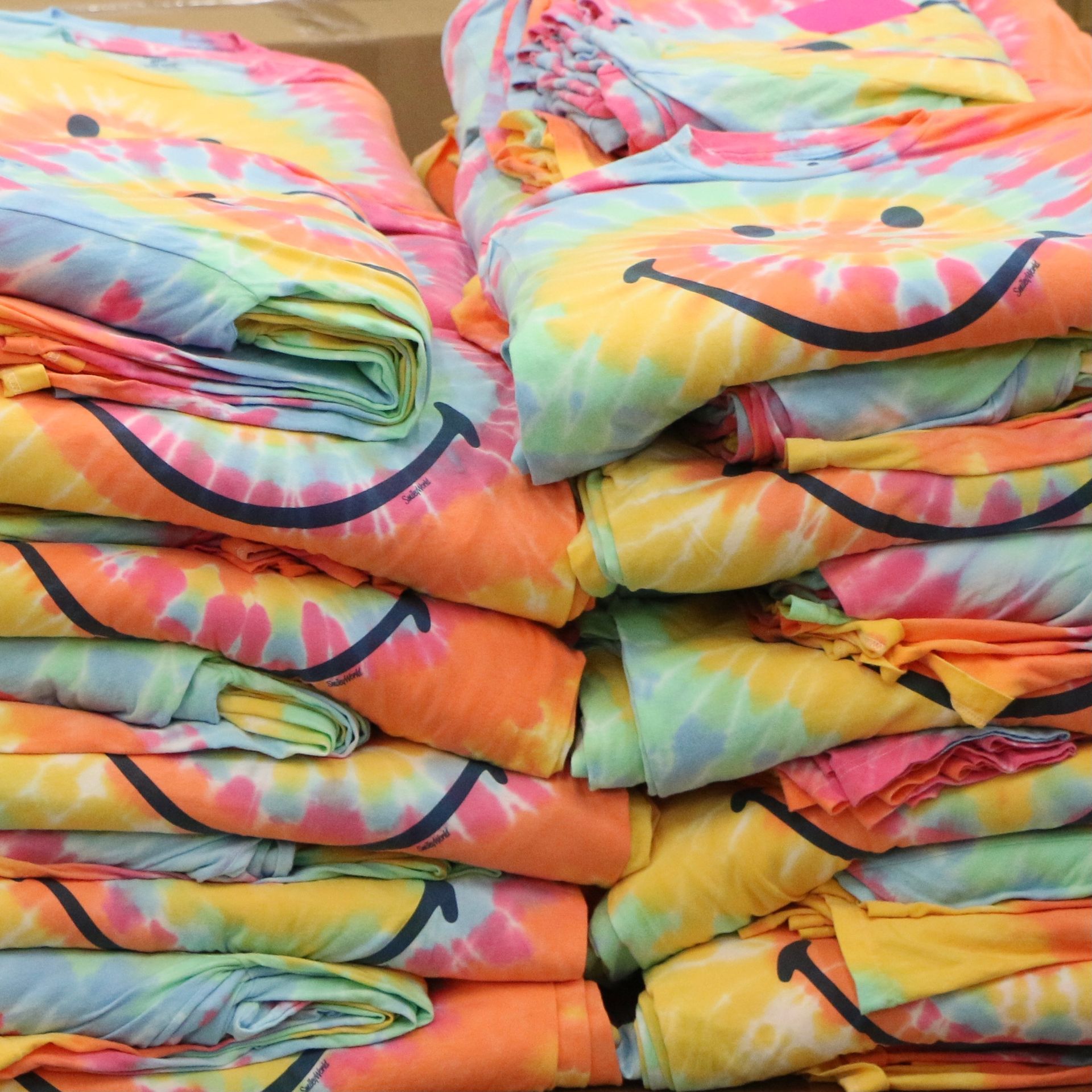 A stack of tie dye shirts with smiley faces on them