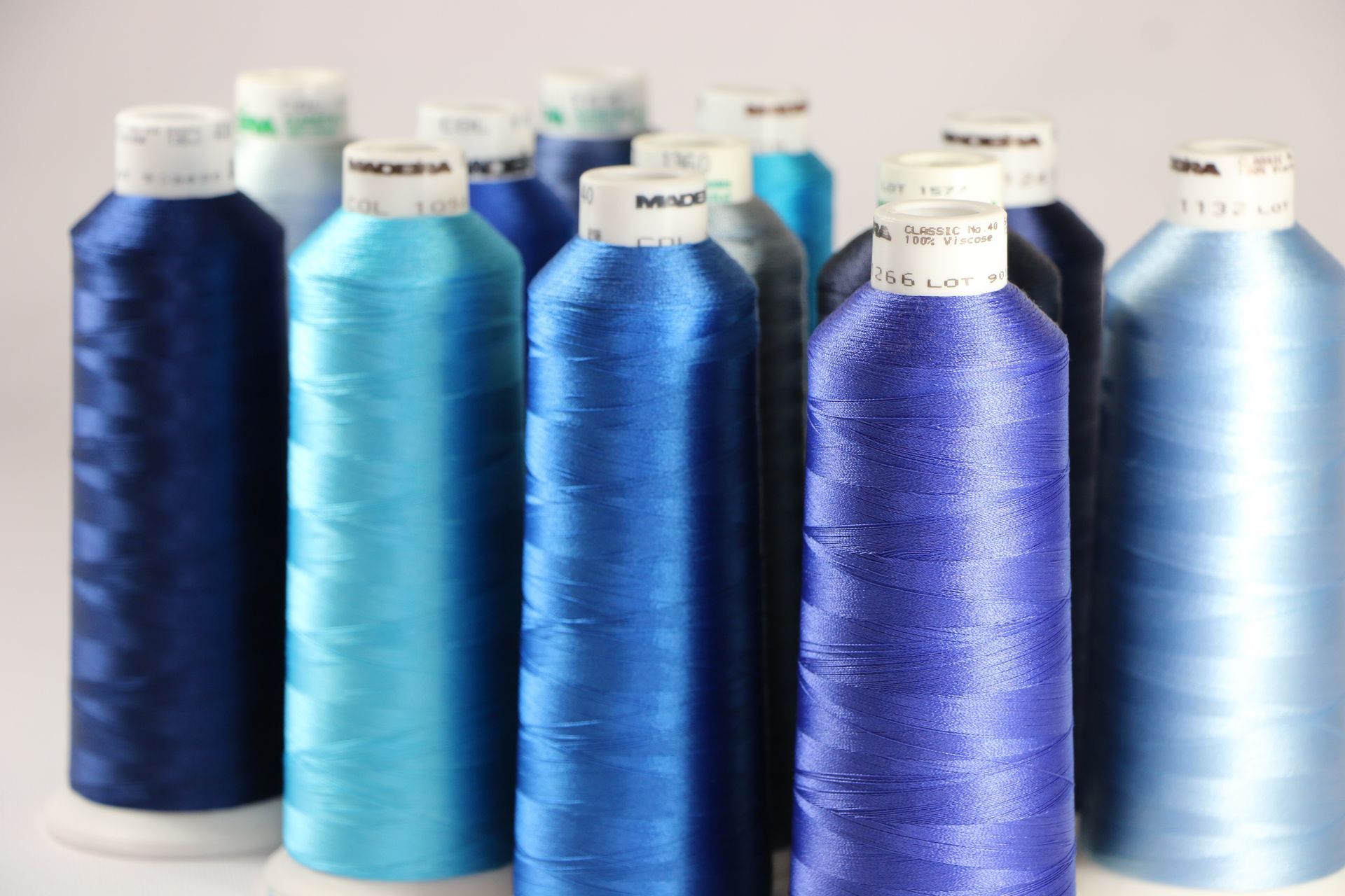 Several bottles of blue thread are lined up in a row