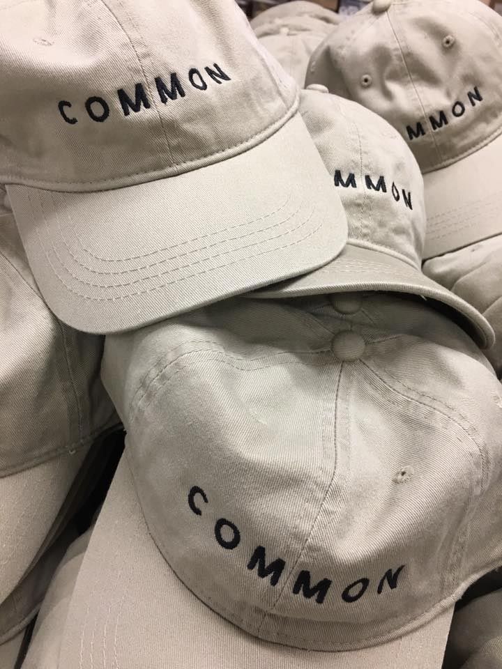 A bunch of baseball caps with the word common embroidered on them