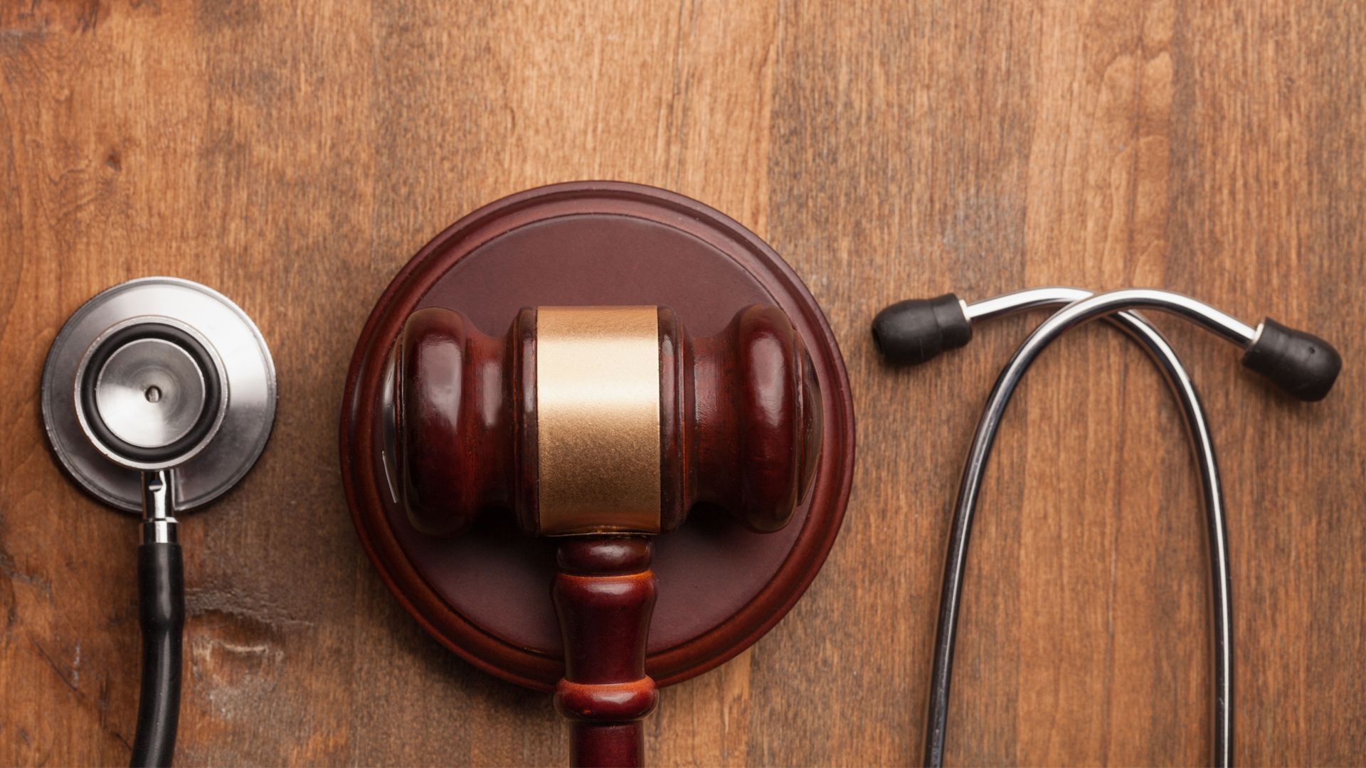 A wooden judge's gavel and a stethoscope on a wooden table