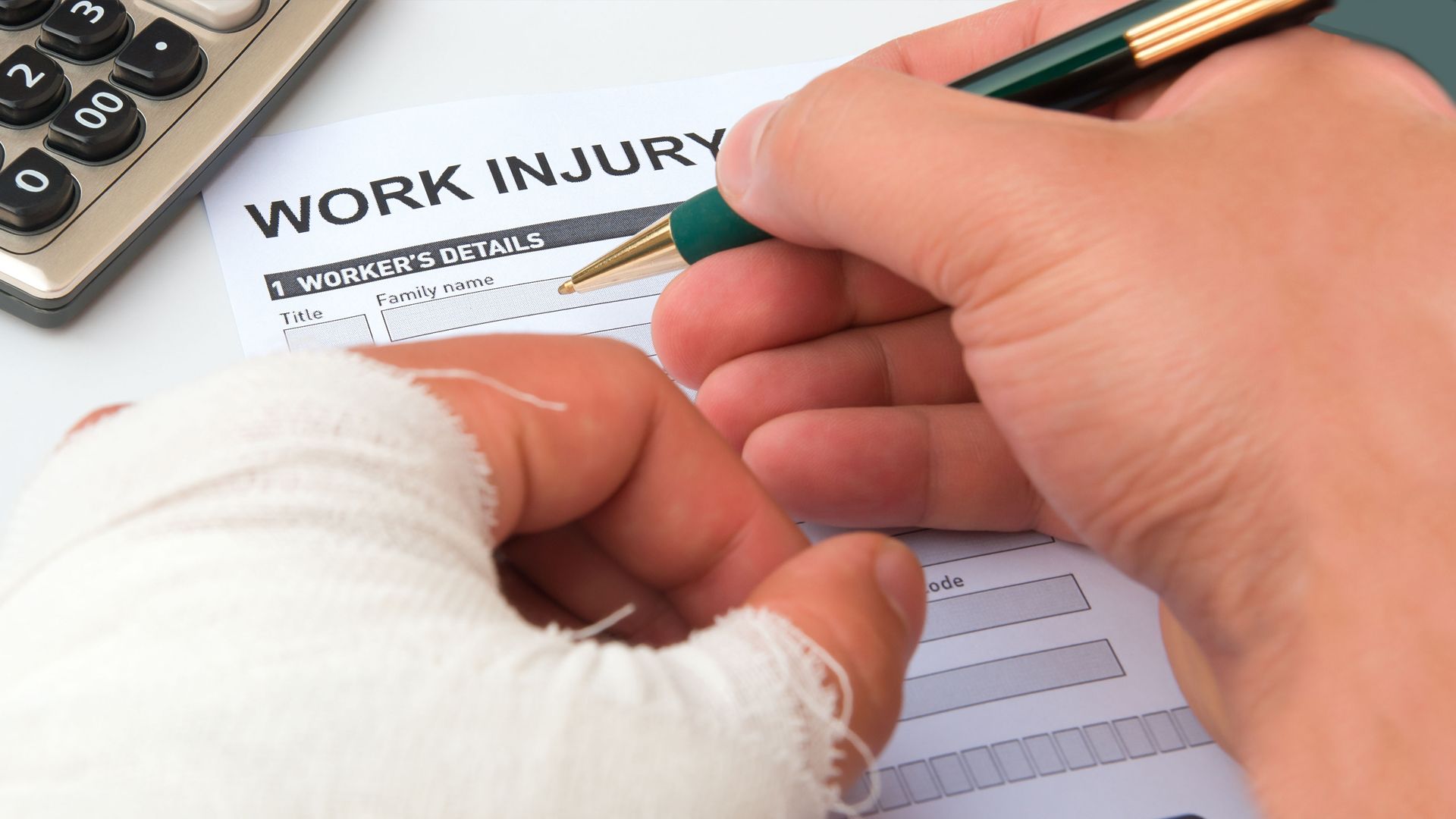 A person with a bandaged hand is filling out a work injury form