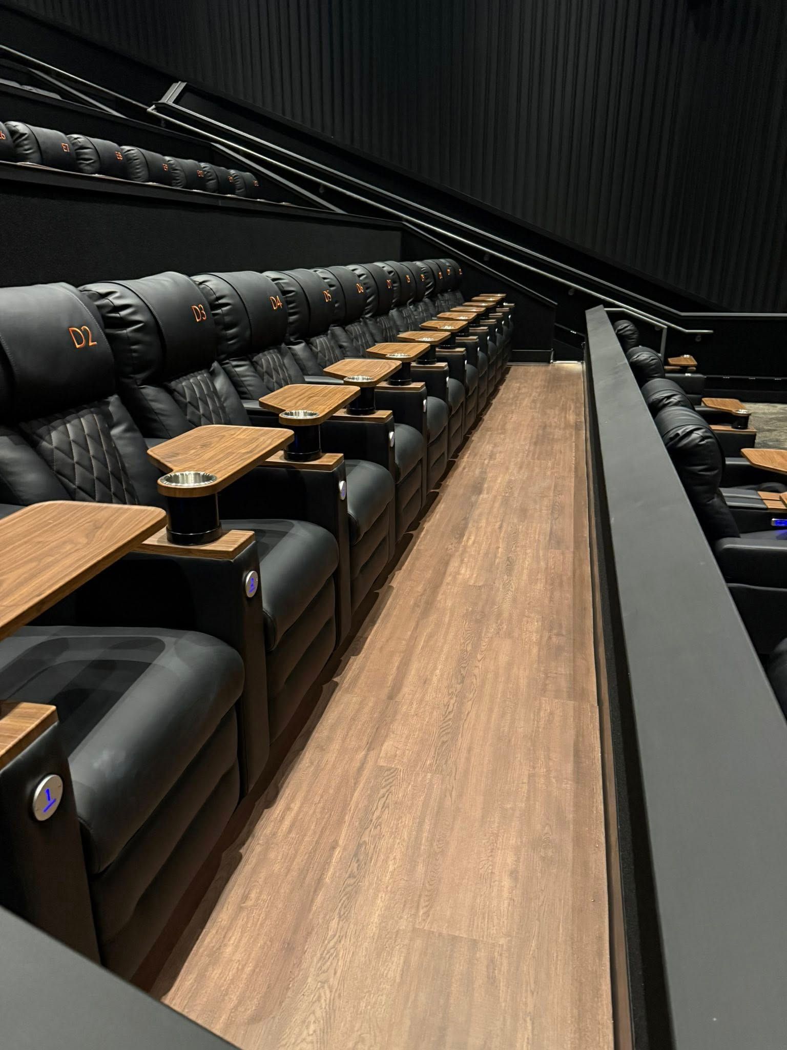 Empty modern auditorium with black seats and wooden fold-out desks along a central aisle