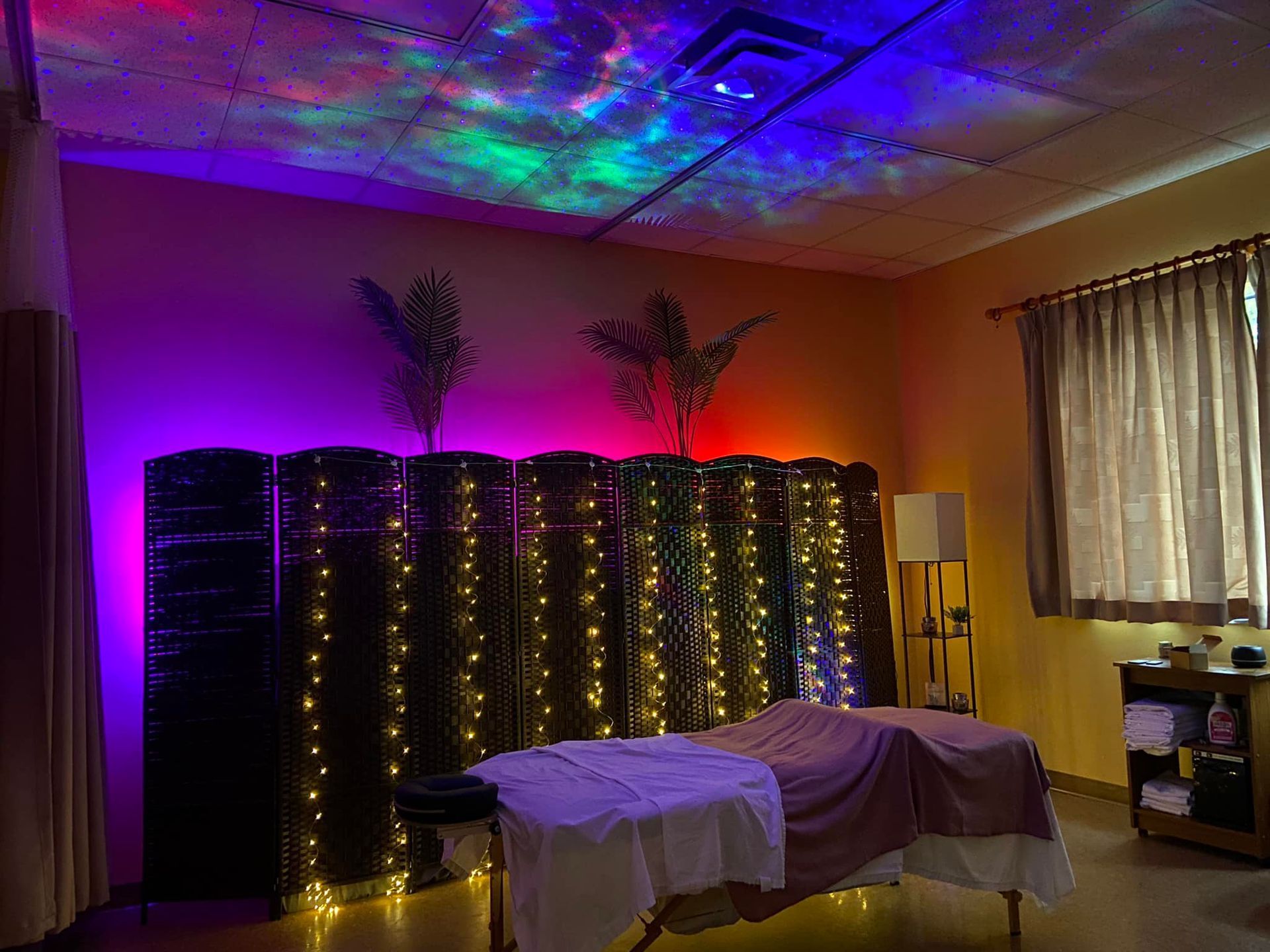 A room with a massage table and a projector on the ceiling.