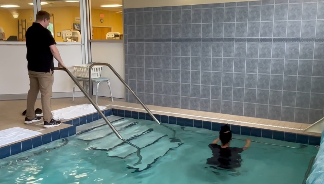 A man is standing next to a woman in a swimming pool.
