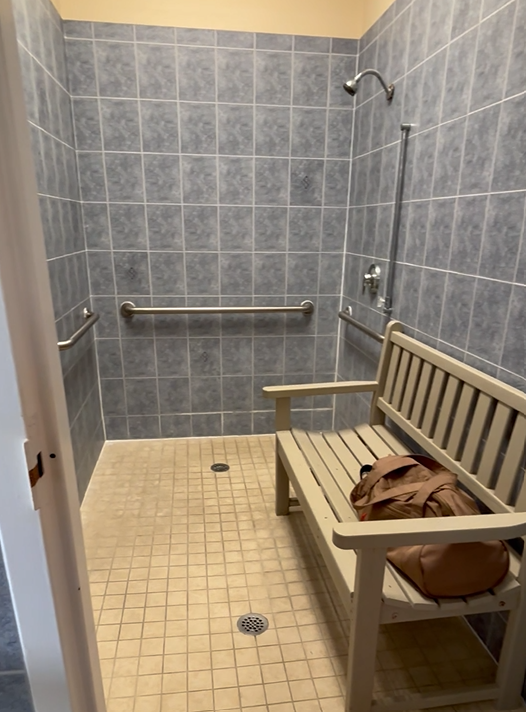 A shower with a bench and a bag on it