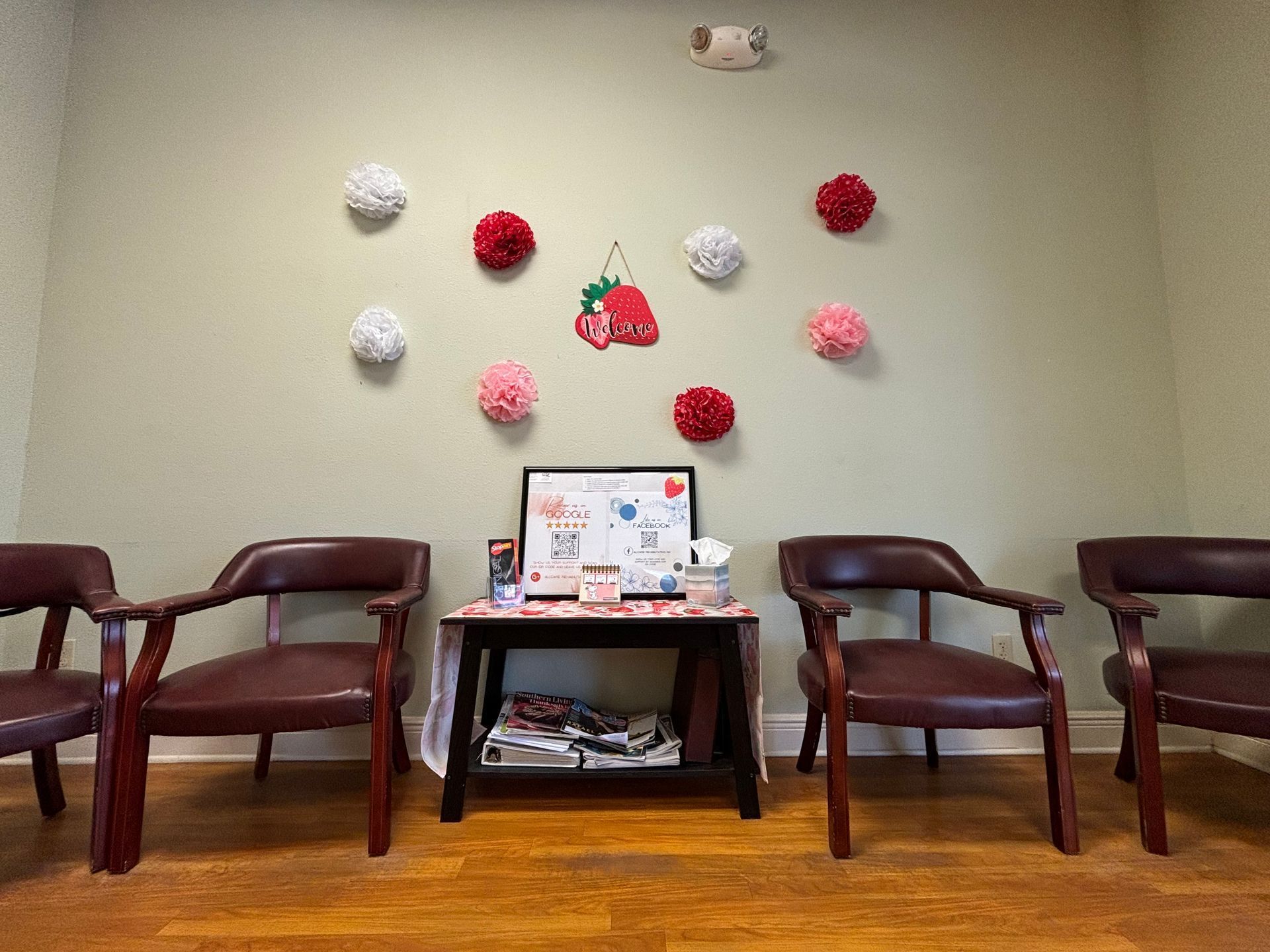 A waiting room with chairs and a table with flowers on the wall.