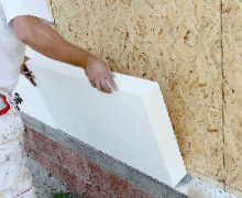 Worker placing sheet insulation to the wall