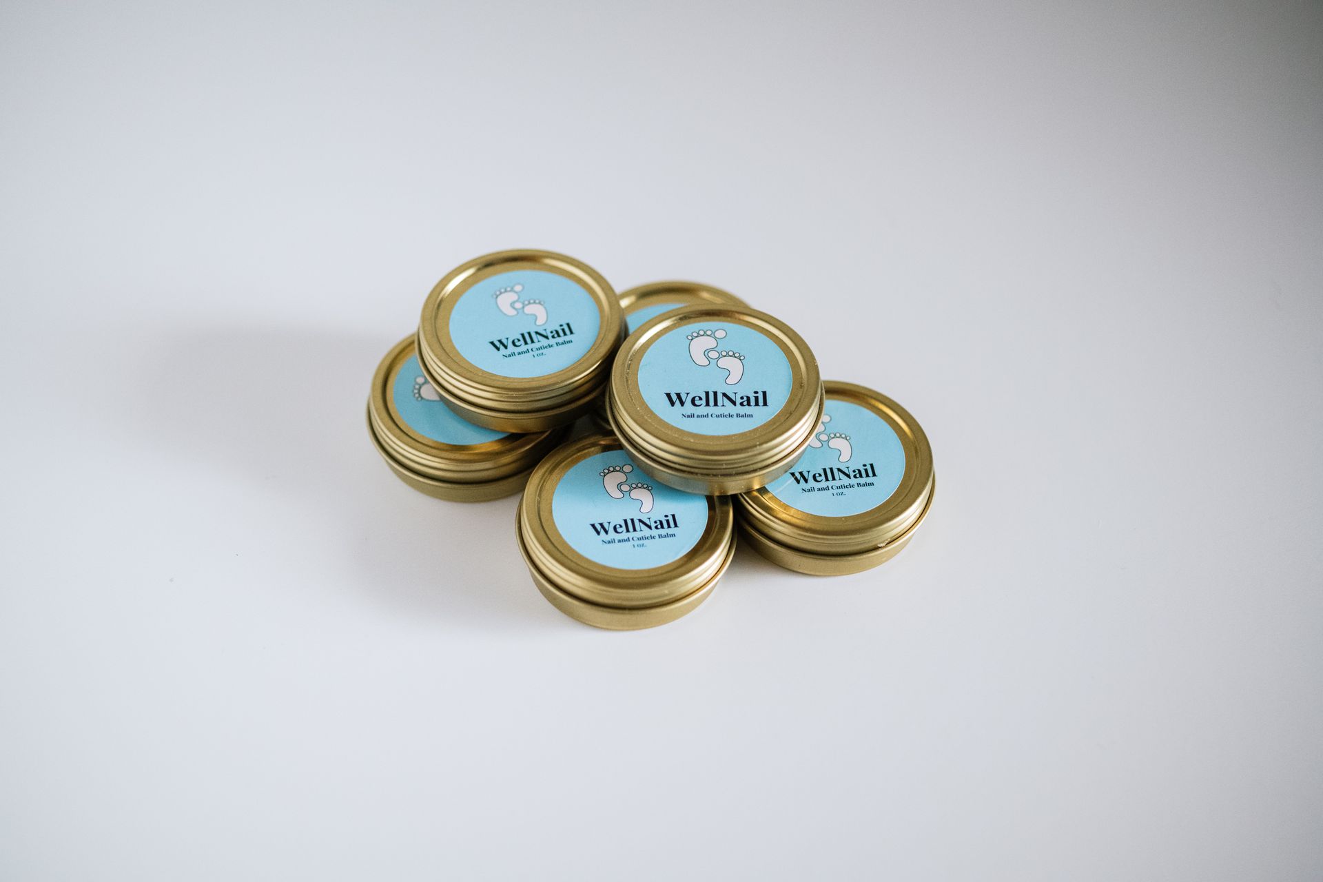 Six small, gold-rimmed tins with light blue lids and a white unicorn illustration, piled together.