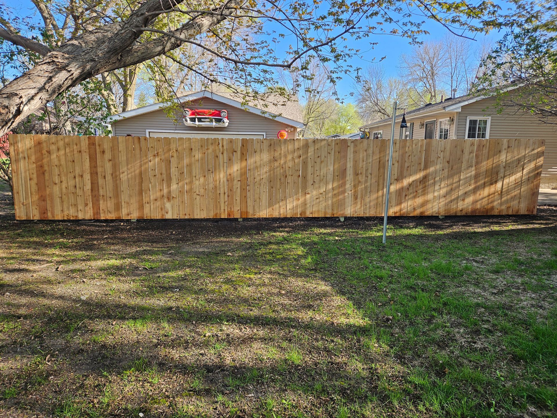 Wooden privacy fence across a backyard with houses and trees behind it