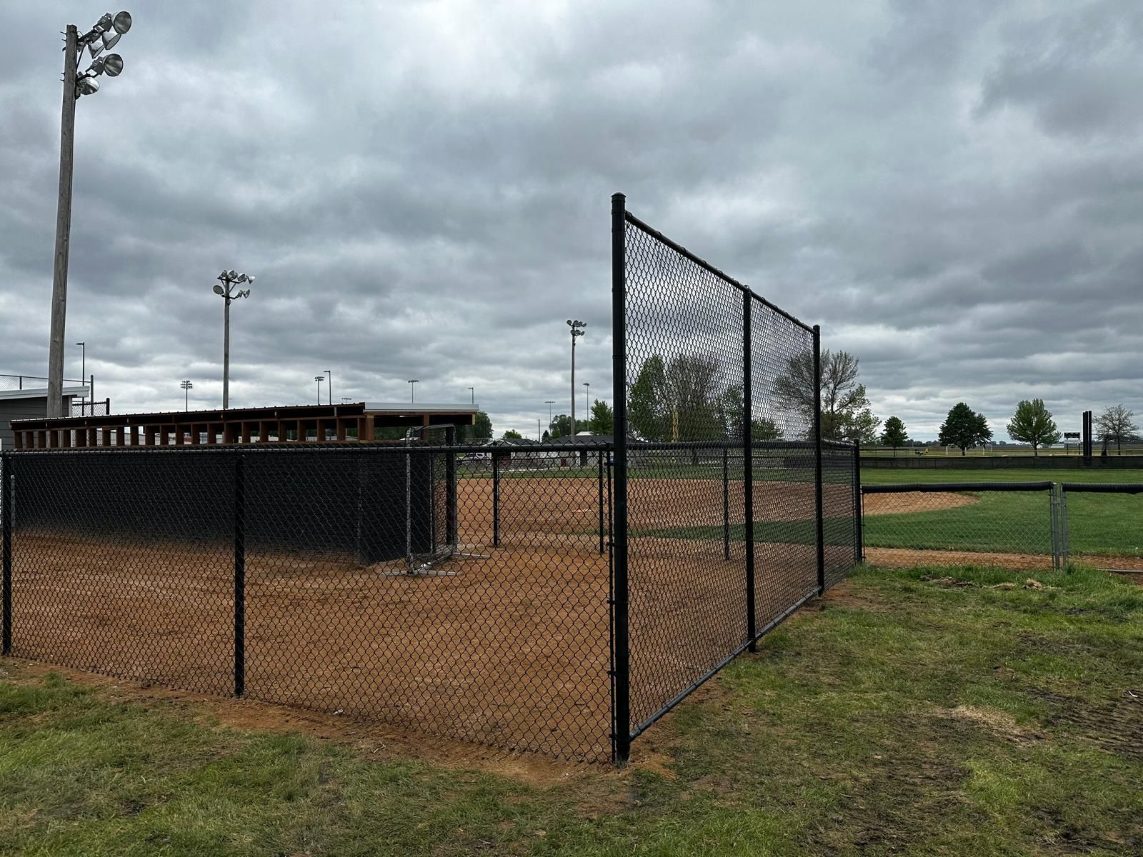 Empty baseball field with chain-link fencing and overcast sky