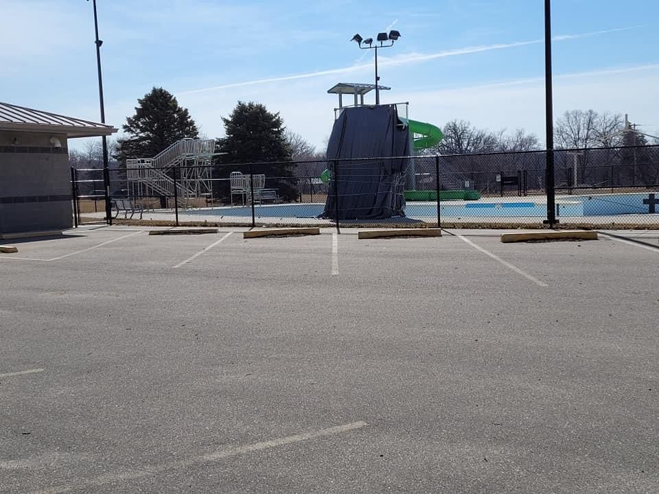 Empty parking lot with a tall diving platform and pool area in the background