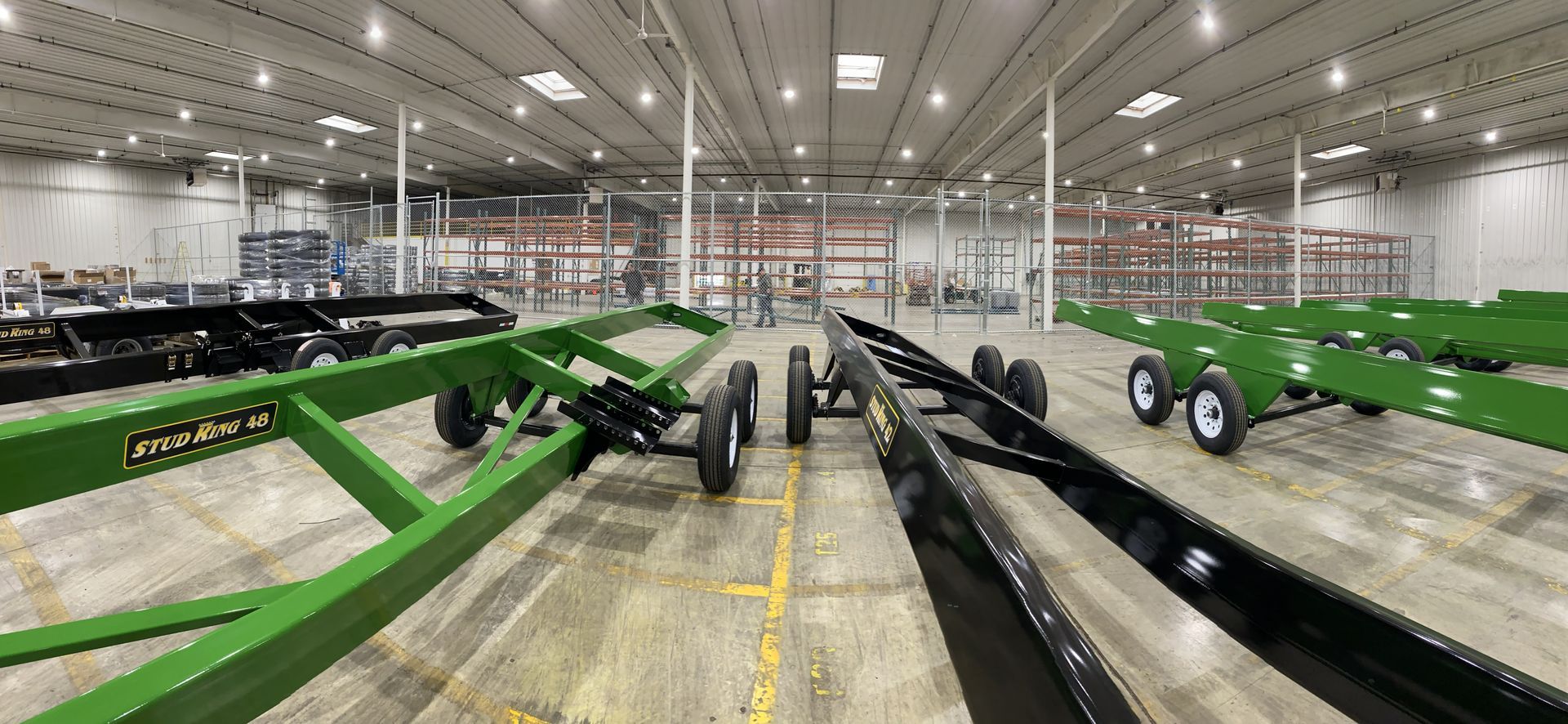 Large warehouse with rows of green agricultural equipment on display