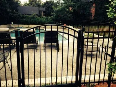 Black metal patio gate in front of outdoor seating on a sunny terrace