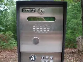 Outdoor silver payphone with keypad and coin slot in a wooded area