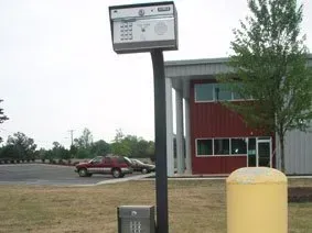 Parking lot sign beside red car and building with yellow post in foreground