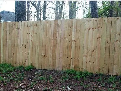 New wooden privacy fence along a yard with trees visible behind it