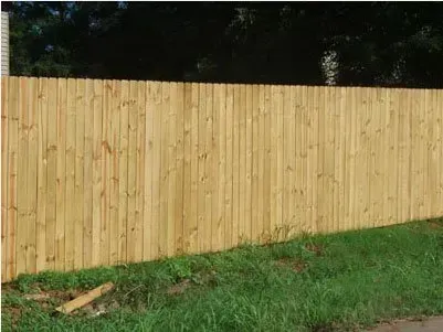 Wooden privacy fence beside a grassy yard with trees in the background.