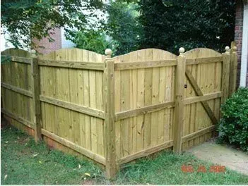 Wooden backyard gate and privacy fence with arched top panels and diagonal brace