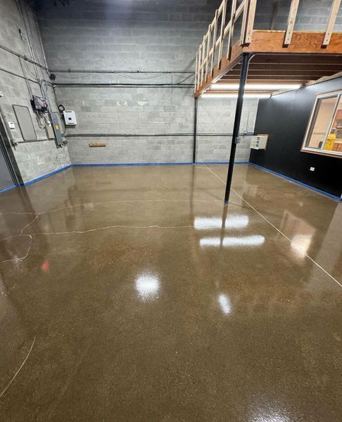 A polished, high-gloss concrete floor in a room with gray block walls and a wooden loft structure above.