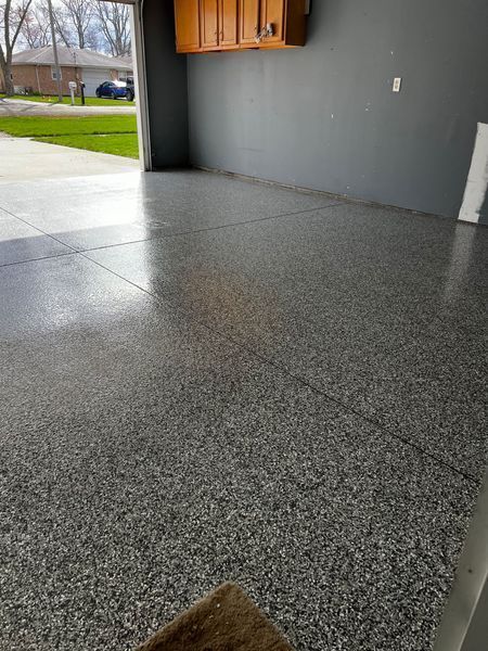 A freshly coated gray speckled epoxy garage floor looking out onto a residential street.