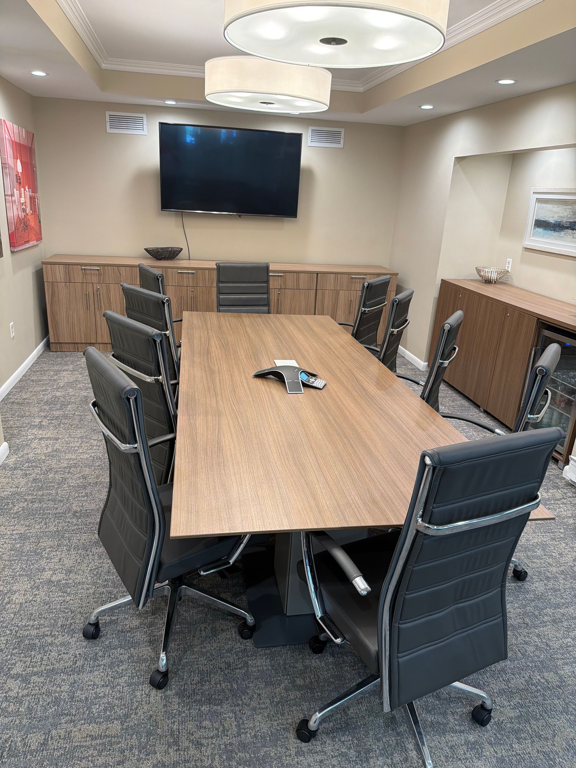 Conference room with wood table, black chairs, and wall-mounted TV