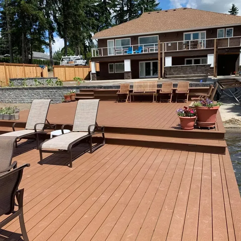 Brown house with deck, lounge chairs, and lake view.