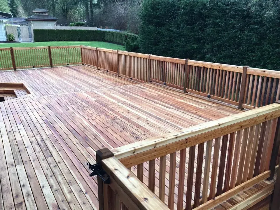 Wooden deck with railing overlooking a green yard.
