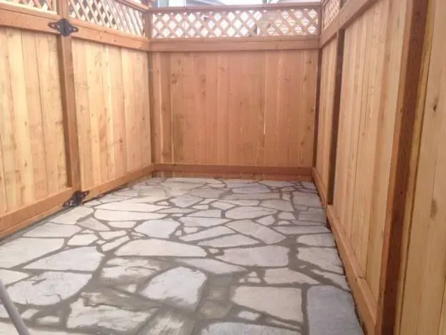 Small backyard patio with flagstone floor, surrounded by wooden fence.