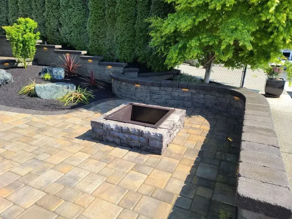 Stone patio with fire pit, curved retaining wall, steps, and lush landscaping.