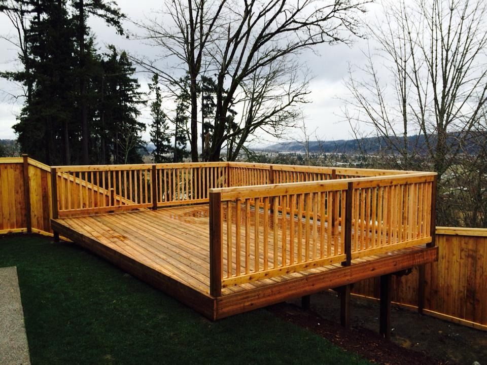 Wooden deck with railings in a yard with trees and a view.
