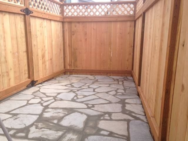 Enclosed outdoor patio with flagstone floor and wooden fence.