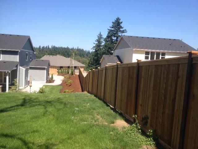 Wooden fence bordering green lawn in a sunny residential neighborhood.