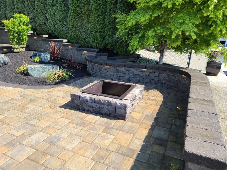 Stone patio with fire pit, retaining walls, and landscaping.