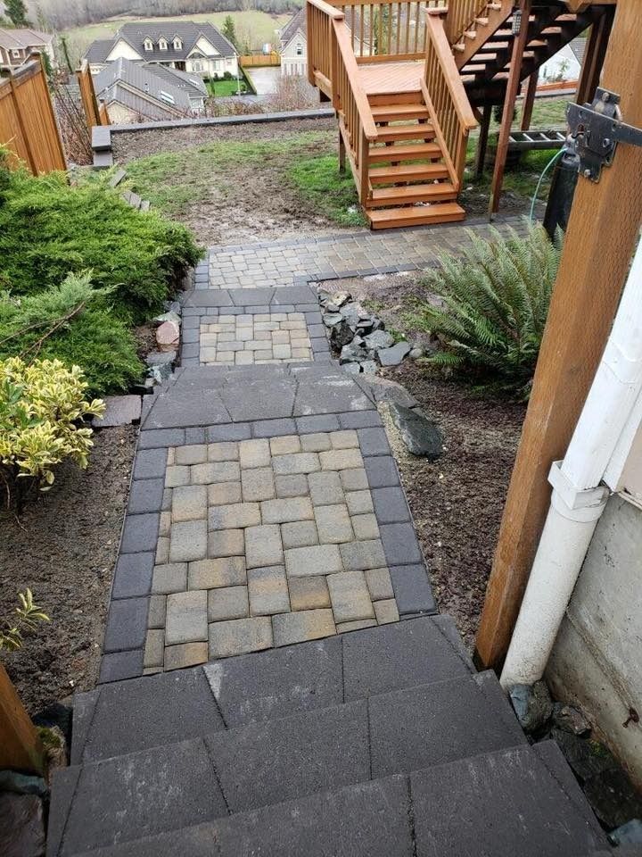 Stone steps leading down a hillside, with pavers and wooden stairs at the top.