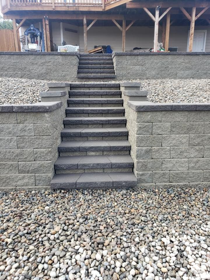 Stone steps and retaining walls leading to a house. Gray blocks, gravel ground.