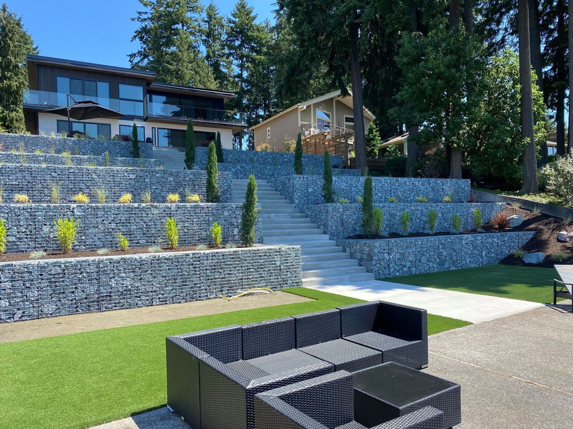 Terraced landscape with stone walls, stairs, and homes, with a black patio set in the foreground.