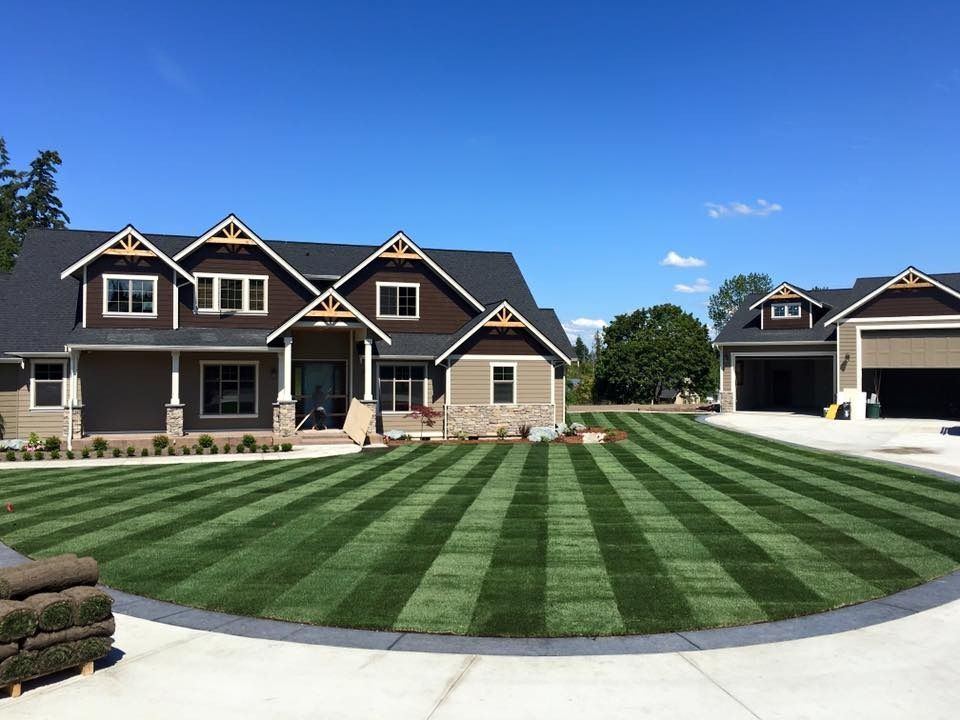 House with striped green lawn and clear blue sky.